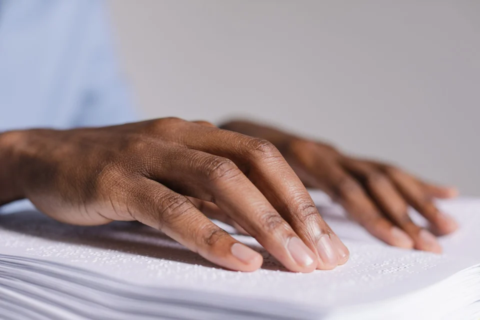 Hands reading a page of Braille text