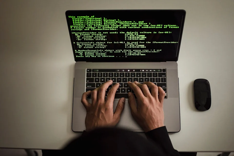 Hands working on code on a laptop screen