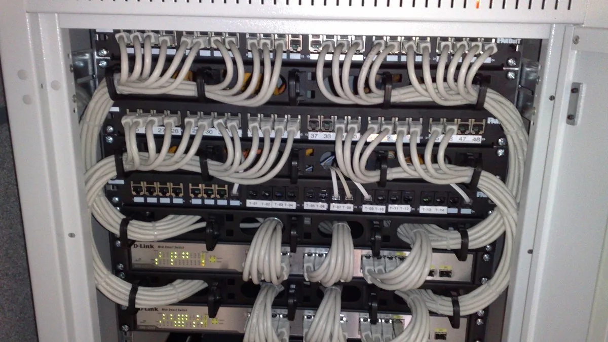 Network switches and patch panels in a server rack, connected with white Ethernet cables